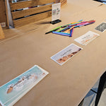 Table with printed materials and stationery items in a workshop setting
